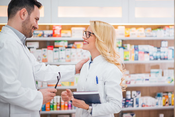 Smiling blonde intern pharmacist talking to her boss.