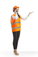 Destroying gender stereotypes. Female builder in orange helmet standing with phone on white studio background. Safety specialist, engineer, occupation, businesswoman, job concept. Woman in the male