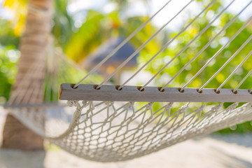 Closeup of tropical holiday concept as hammock with palm leaves blurred tropical beach background....