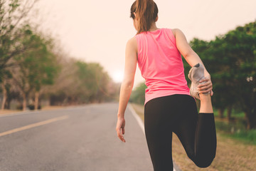 Women warm up exercises before running jogging during sunset at road park