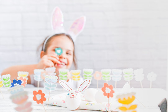 Little girl with bunny ears and easter decoration and eggs on a white background. Cheerful baby on holiday. Free space for text. Copy space.