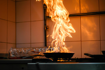 The chef cooking and makes a fire in a pan. Cooking with fire. Crown food. Charismatic chef in the kitchen.