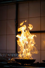 The chef cooking and makes a fire in a pan. Cooking with fire. Crown food. Charismatic chef in the...