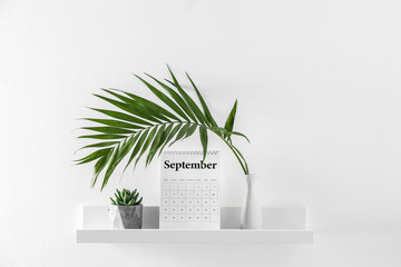 Flip calendar and vase with tropical leaf on shelf