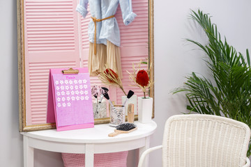 Calendar with female accessories on table in room
