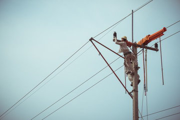 Two linemans use devices that are insulated for maintenance high voltage distribution system. To...