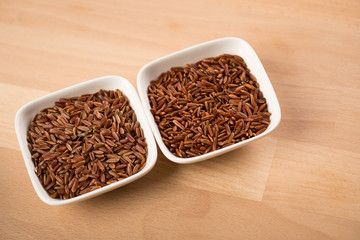 Rotschaliger roher roter Reis aus Piemont Italien und roter Jasmin Reis aus Kambodscha Asien in Porzellan Schale sind Spezialitäten