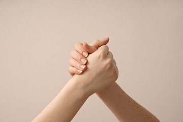 Women holding hands on light background