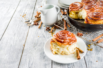 Homemade baking, Cinnamon rolls with sugar frosting. With cinnamon sticks and spices, wooden background copy space