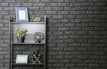 Modern shelf unit near dark brick wall