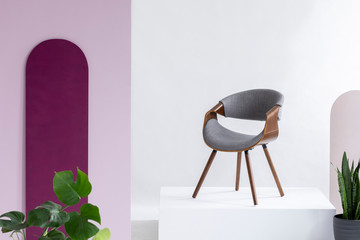 Real photo of a gray, fleece and leather chair standing on a podium in a living room interior with...