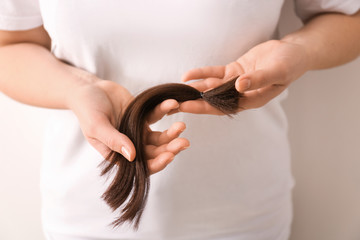 Woman with hair strand on light background, closeup. Concept of donation