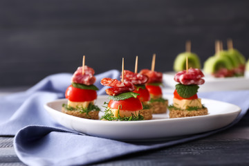 Plate with tasty canapes on wooden table