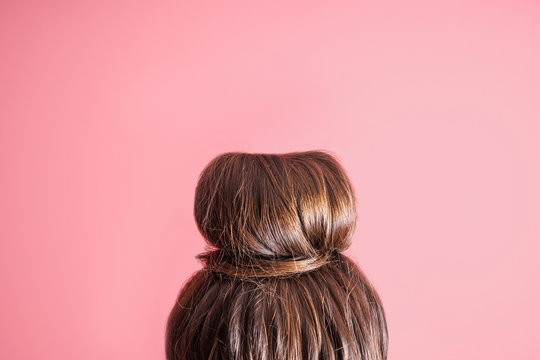 Young woman with hair bun on color background