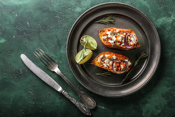 Plate with baked sweet potato on color background