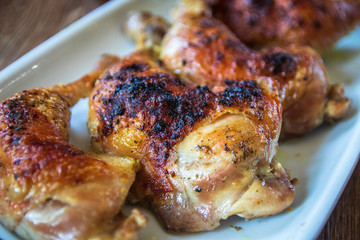 Roasted chicken legs on wooden table. Close-up.