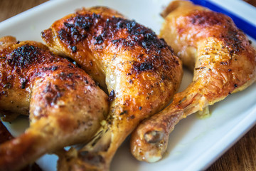 Roasted chicken legs on wooden table. Close-up.