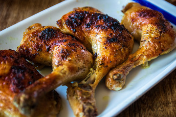 Roasted chicken legs on wooden table. Close-up.