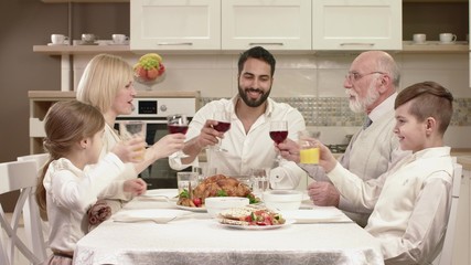 Family Sitting Around a Table, Eating, Communicating and Having Fun during Family Dinner.