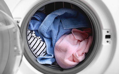 Modern washing machine with laundry, closeup