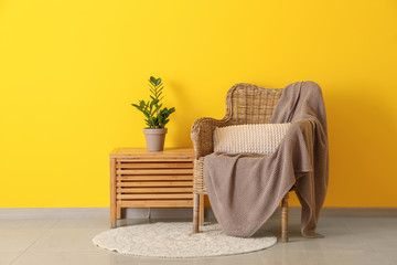 Armchair with table near color wall