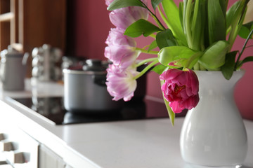 Vase with beautiful flowers on counter in kitchen