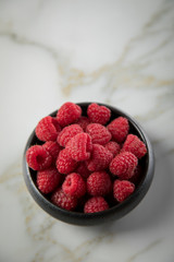 Himbeeren in schwarzer Porzellan Schale auf Marmor Hintergrund