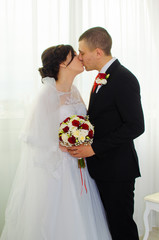 wedding photoshoot in the Studio. the bride and groom posing. groom with a red tie and black business suit. the bride in a white lush dress