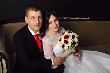 wedding photoshoot in the Studio. the bride and groom posing. groom with a red tie and black...