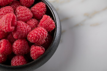 Himbeeren in schwarzer Porzellan Schale auf Marmor Hintergrund