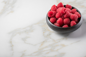 Himbeeren in schwarzer Porzellan Schale auf Marmor Hintergrund