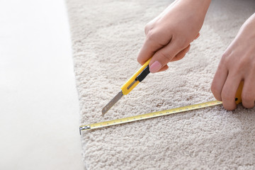 Woman with tape measure cutting carpet