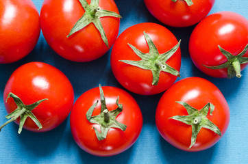 Bright organic tomatoes on a blue background. - Image