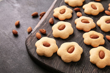 Wooden board with tasty cookies on dark table, closeup