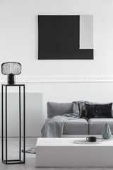 Grey blanket and black pillow on comfortable sofa in stylish living room interior