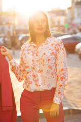 Fashionable young model wearing costume and blouse posing with soft evening sunlight