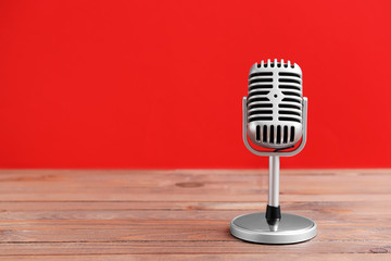 Retro microphone on table against color background