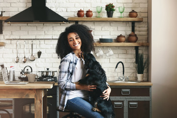 African-American woman with cute funny dog in kitchen