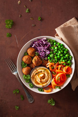 healthy vegan lunch bowl with falafel hummus carrot ribbons cabbage and peas