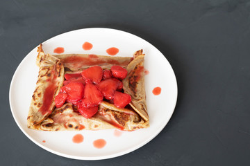 Galette Bretonne with strawberries on a white plate. Copy space. Buckwheat flour pancakes.