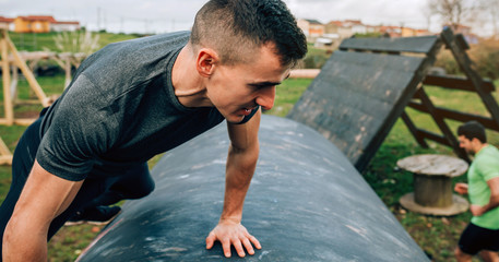 Male participant in an obstacle course climbing a drum