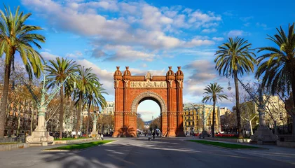 Poster Triumphal Arch in Barcelona, Catalonia, Spain. Arc de Triomf at boulevard street. Alley with tropical palm trees. Early morning landscape with shadows and blue sky with clouds. Famous landmark. © Yasonya