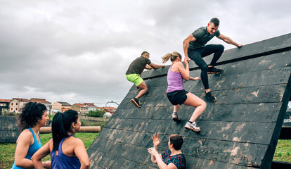 Group of participants in an obstacle course climbing a pyramid obstacle