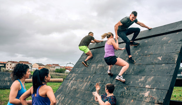 Group of participants in an obstacle course climbing a pyramid obstacle