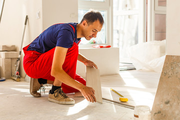 Tiler installing ceramic tiles on a floor