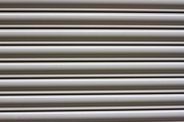 Metal covering for a parking garage gate in alternating round thick and slim lines