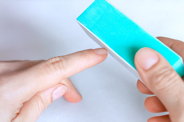 Woman buffing natural unpainted nails with nail buffer.