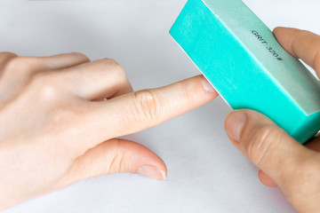 Woman buffing natural unpainted nails with buffer block.