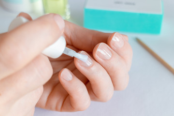 Woman doing at-home manicure, applying nail conditioner or base coat. - 257436029