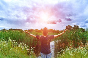 Holiday in the spring. Girl in the sun on nature. Beautiful clouds. Freedom